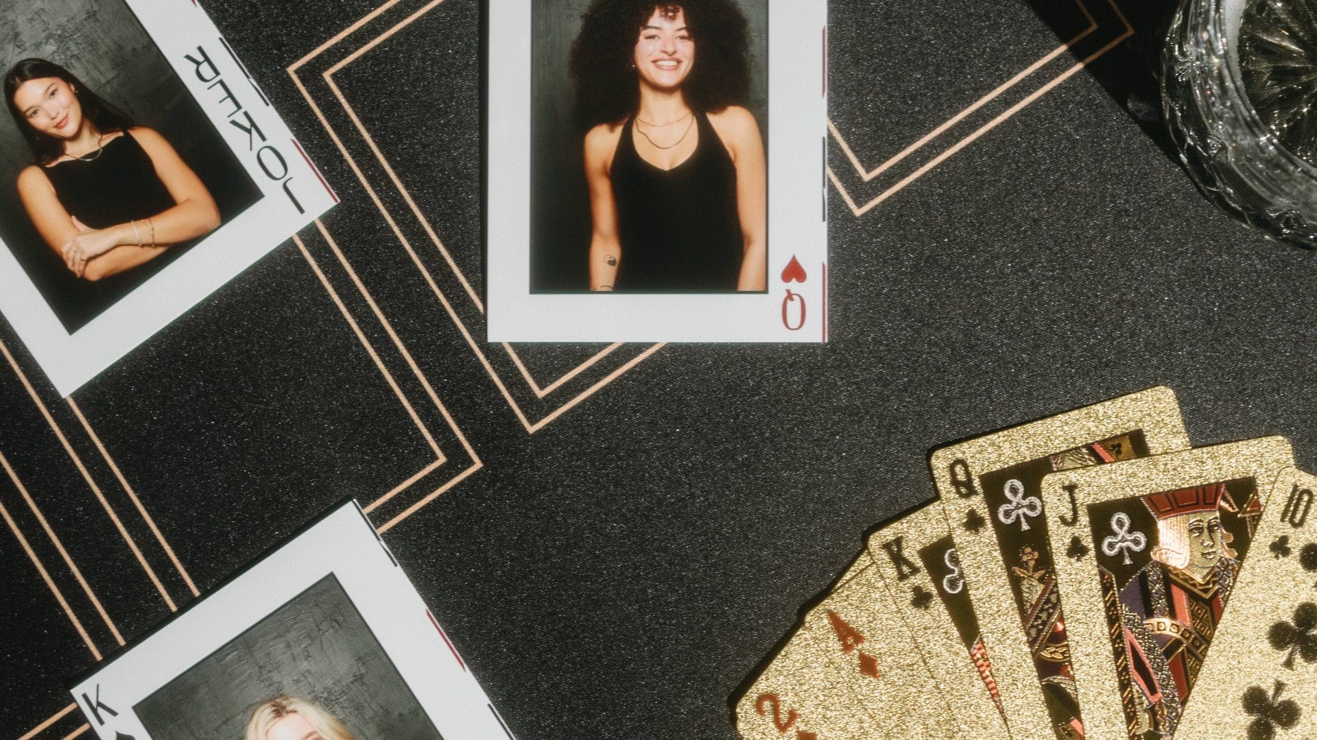 Poker-themed flat lay with playing cards, personal photos, poker chips, and drinks on a dark surface.