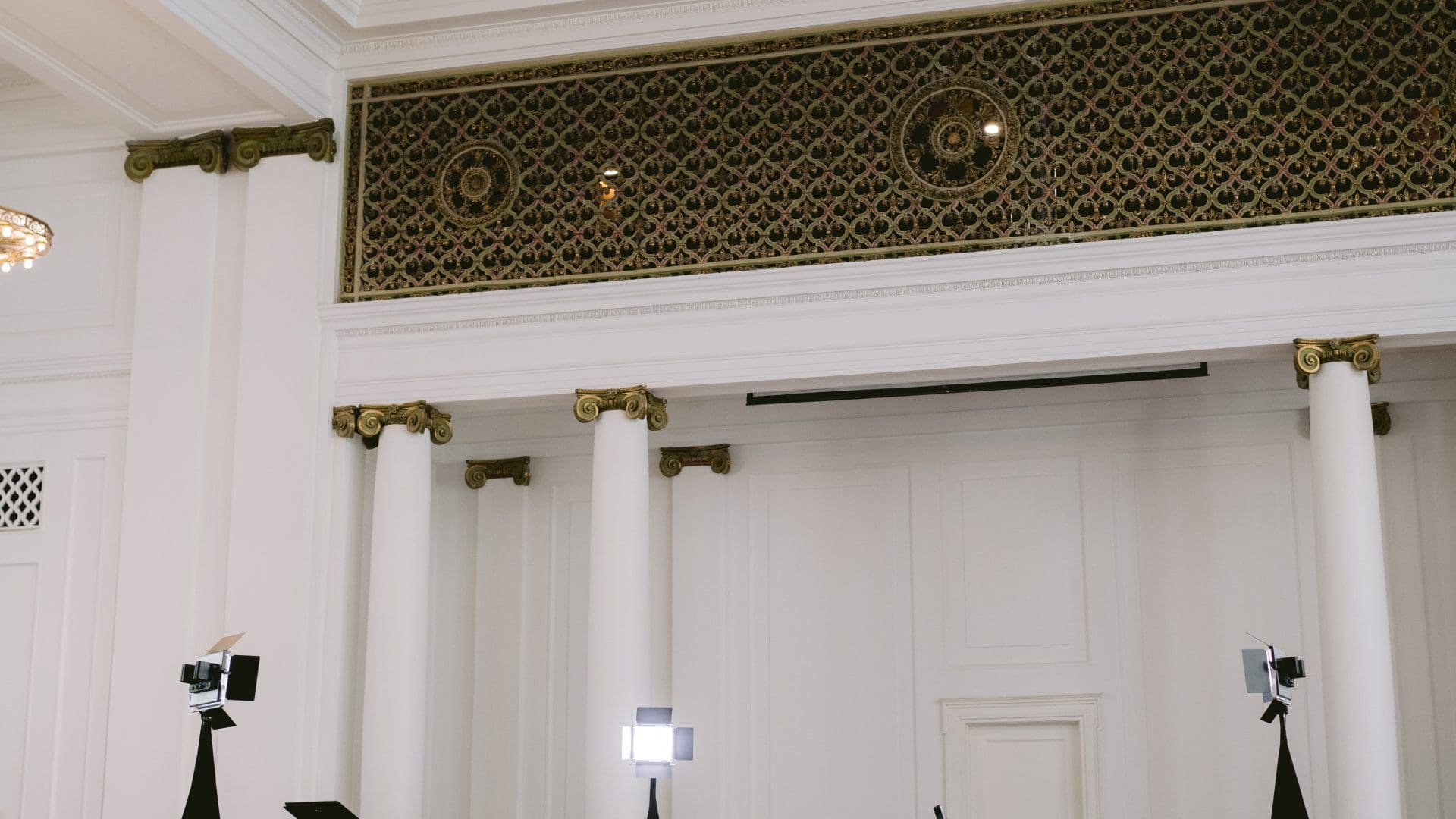 Elegant hall with a grand piano, lighting equipment, and decorative columns, perfect venue for events or concerts.